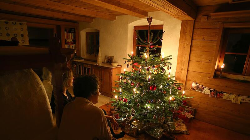 Familie sitzt vor einem beleuchteten Weihnachtsbaum