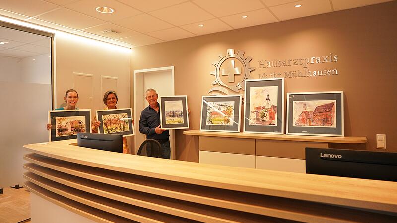 Frauke Kosteletzky, K&uuml;nstlerin Ulrike Polifke und Gr&uuml;ndungsmitglied der B&uuml;rgergenossenschaft Markt M&uuml;hlhausen Reinhard Klaus (von links) mit den Kunstwerken  in der Praxis. in M&uuml;hlhausen.