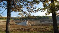 Die Grundsperre in der linken Bildh&auml;lfte ist ein Wall aus Steinen &ndash; ein Damm vor dem Damm, der k&uuml;nftig unter dem Wasser verschwinden wird.