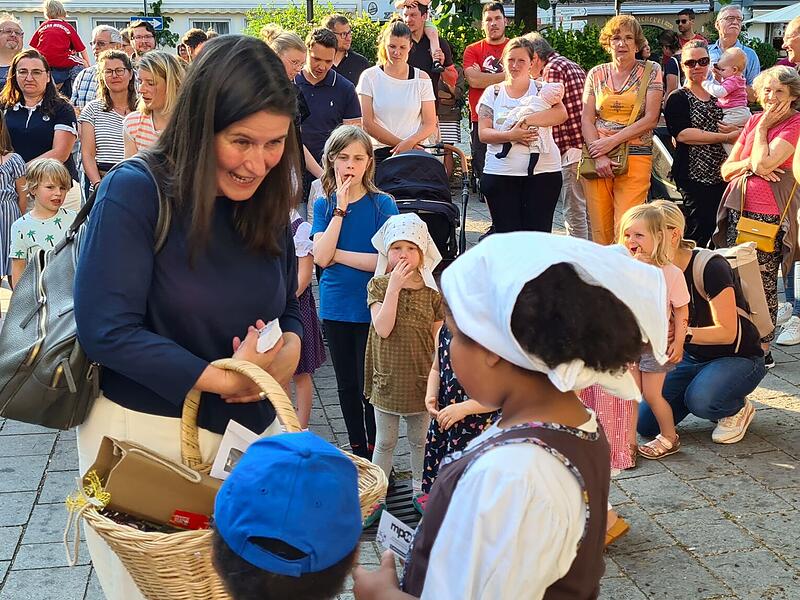 Die Bürgermeisterin teilt Süßigkeiten an die Kinder aus. Die Bürgermeisterin teilt Süßigkeiten an die Kinder aus.