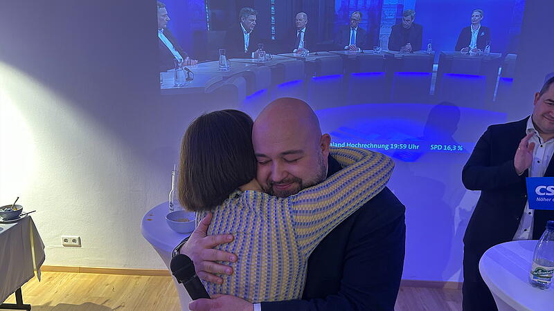 Bundestagswahl 2025 Coburg Jonas Geissler umarmt nach seinem erneuten Mandatsgewinn für den Bundestag bei der Wahlparty in Coburg Ehefrau Anne-Sophie Göbel.