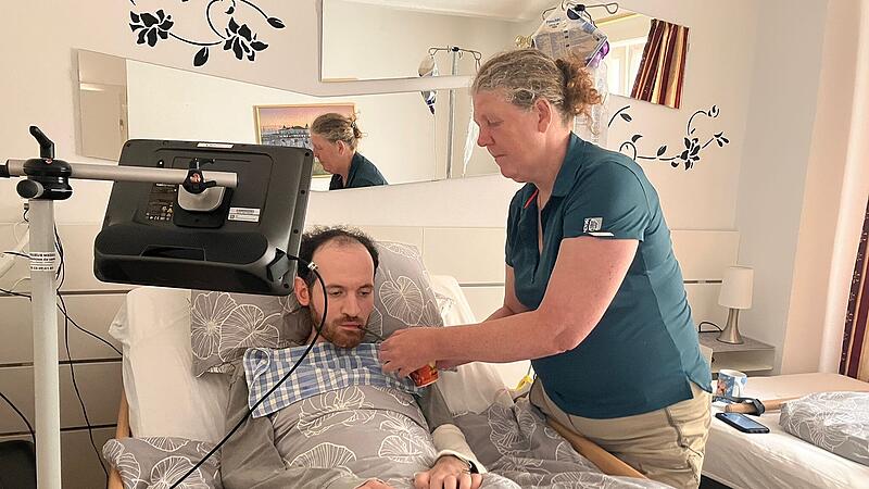 ALS-Patient Katja Heußel hilft ihrem Freund Jean, der in einem Krankenbett liegt. Der an ALS erkrankte Franzose hat einer Veröffentlichung dieses Fotos ausdrücklich zugestimmt. Denn er möchte auf diese tödliche Nervenerkrankung aufmerksam machen.