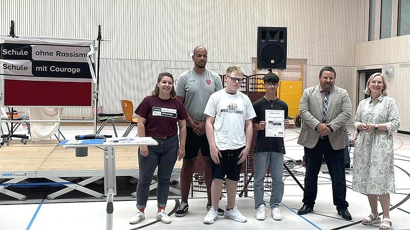 Lea Hattenbach (links), Regionalkoordinatorin von "Schule ohne Rassismus – Schule mit Courage"-Unterfranken überreicht der D. -Paul-Eber-Mittelschule die Urkunde, mit der sich die Schule zum Engagement für Courage und gegen Rassismus verpflichtet. Die Urkunde wurde von Konrektorin Petra Krämer (von rechts), Rektor Fabian Forster, Wertebotschafter Mika Schmerbeck, Schülersprecher Jorgos Karakalides und Schulpate Alex King entgegengenommen. Lea Hattenbach (links), Regionalkoordinatorin von "Schule ohne Rassismus – Schule mit Courage"-Unterfranken überreicht der D. -Paul-Eber-Mittelschule die Urkunde, mit der sich die Schule zum Engagement für Courage und gegen Rassismus verpflichtet. Die Urkunde wurde von Konrektorin Petra Krämer (von rechts), Rektor Fabian Forster, Wertebotschafter Mika Schmerbeck, Schülersprecher Jorgos Karakalides und Schulpate Alex King entgegengenommen.
