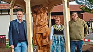 Die Holzskulptur der sagenumwobenen &bdquo;Knellesjungfern&ldquo; von Erwin Fehn hat in einem Pavillon vor der Zecher-Halle ein neues Zuhause gefunden. Dar&uuml;ber freuen sich, von links, B&uuml;rgermeister Daniel Wei&szlig;erth, die Vorsitzende des Volkstrachtenvereins &bdquo;Ze...