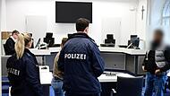 Zwei Polizisten nehmen den Zeugen noch im Gerichtssaal fest.