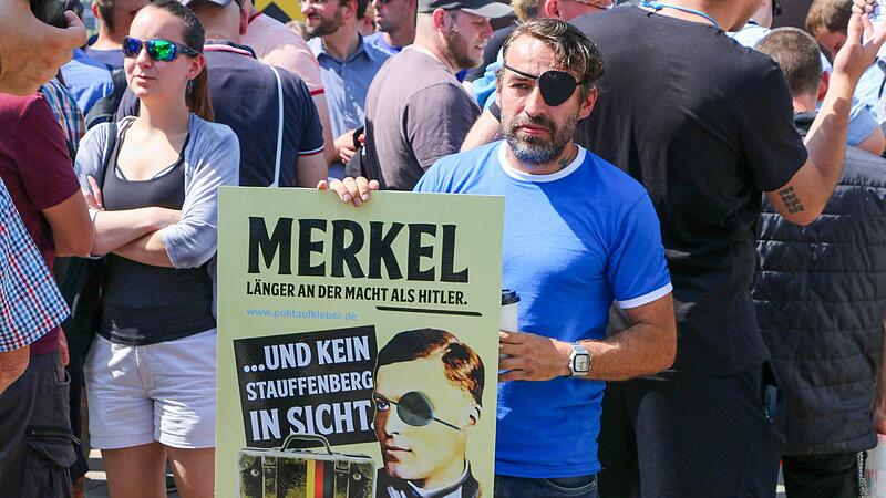 Sven Liebich mit einem Plakat in Halle: „Merkel. Länger an der Macht als Hitler ... und kein Stauffenberg in Sicht“.