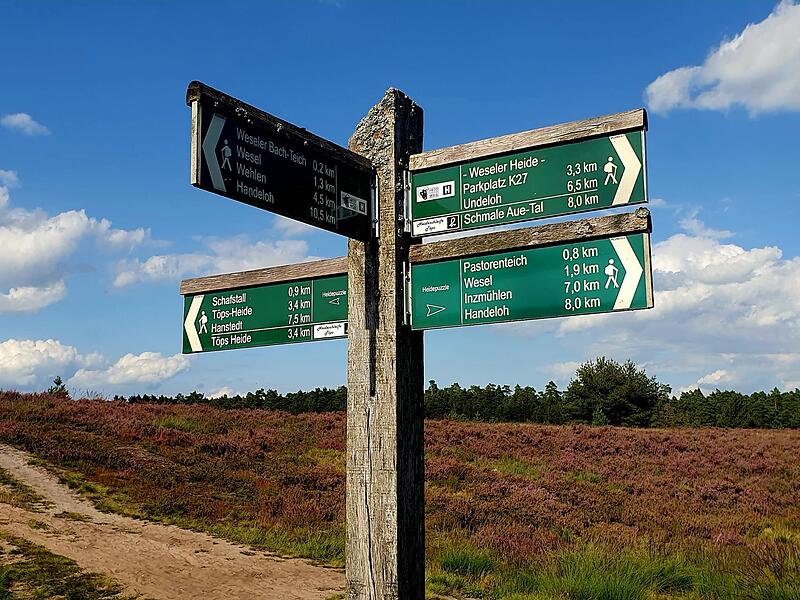 Zahlreiche Wegweiser stehen entlang der Route.2023 Wanderinnen auf dem  Heidschnuckenweg