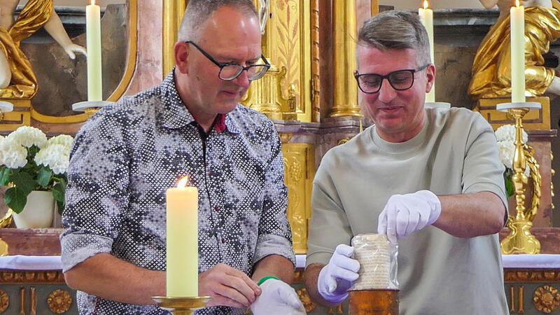 K&uuml;ster Manfred Vogt und Pfarrgemeinderat Stefan Kamm (rechts) &ouml;ffneten die Zeitkapsel, in der ein altes Dokument steckte.