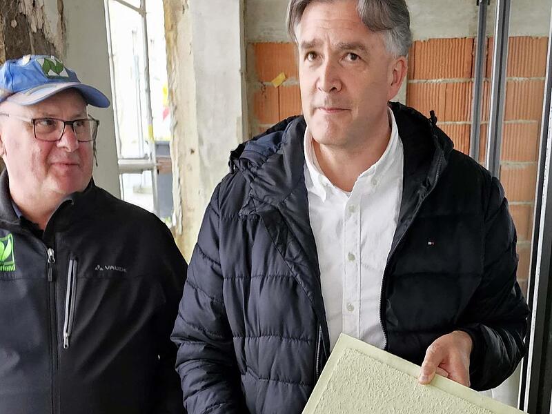 2. Bürgermeister Harald Pascher hält ein Muster in der Hand, welches die Außenfarbe der Xaver-Mayr-Galerie nach Fertigstellung zeigt. Links Stadtrat Klaus Schineller.