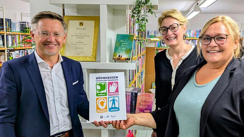 Tobias Reiß, Vizepräsident des Bayerischen Landtags, überreicht die Aktionsplakette „Büchereien: Lernorte der Demokratie“ an Sabine Jentsch (rechts), Leiterin der Bücherei Sassanfahrt. Mit dabei: Dr. Claudia Maria Pecher (Mitte), Leiterin der Landesfachstelle für Büchereien und Bildung.