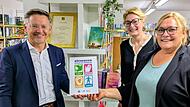 Tobias Reiß, Vizepräsident des Bayerischen Landtags, überreicht die Aktionsplakette „Büchereien: Lernorte der Demokratie“ an Sabine Jentsch (rechts), Leiterin der Bücherei Sassanfahrt. Mit dabei: Dr. Claudia Maria Pecher (Mitte), Leiterin der Landesfachstelle für Büchereien und Bildung.