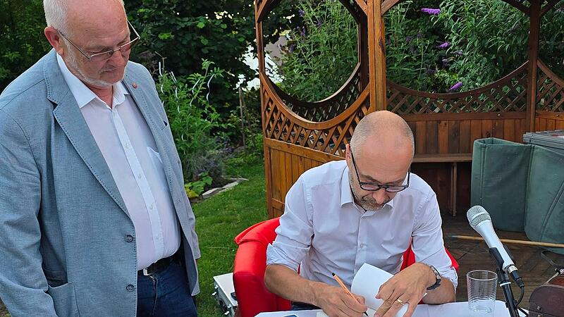 Harry Luck (r.) signiert w&auml;hrend seiner Lesung in Adelsdorf viele B&uuml;cher.
